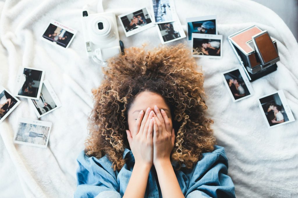 Memory Palace is the Piranha of Memorization, Use for Outrageously Great Performance 7 woman lying on bed covering her face surrounded by photos and white camera