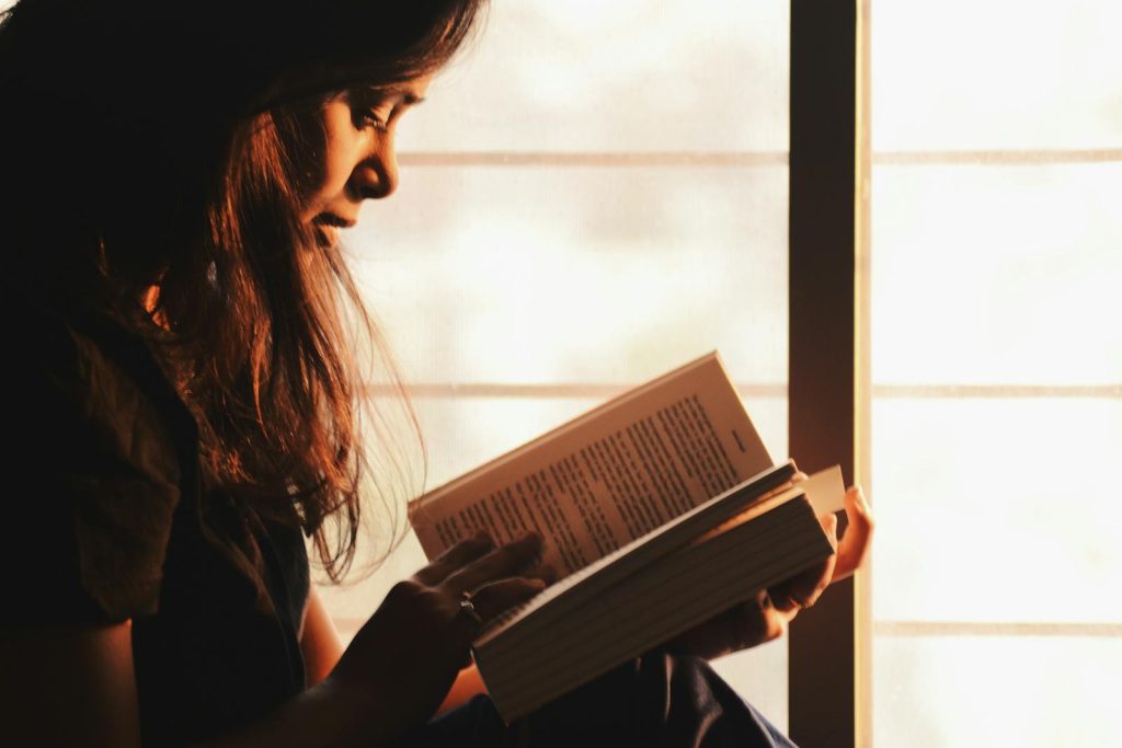 5 Key Benefits of Reading, and Why You Must Start Getting a Book Right Now 6 A woman engrossed in reading a book by a sunlit window creates a serene atmosphere.