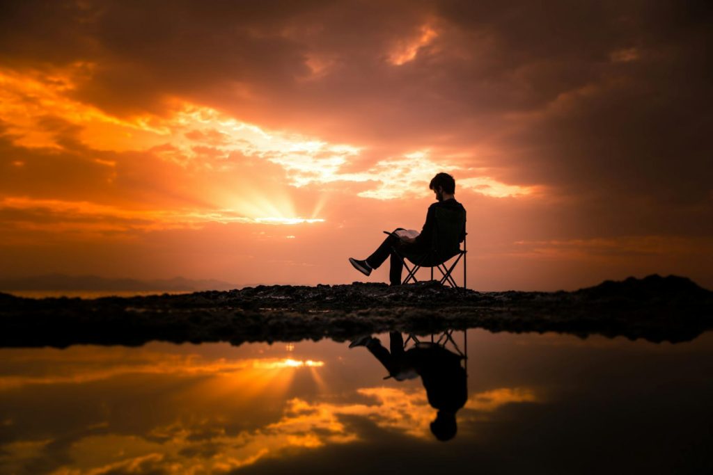 5 Key Benefits of Reading, and Why You Must Start Getting a Book Right Now 5 A person reading on a chair by a reflecting pond at sunset in Korgan, Turkey.