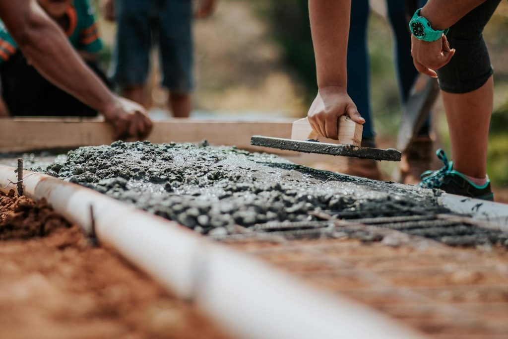 Tens of Thousands of Classrooms Underway as Angara Signs Million-Dollar PPP Deal - Solution to Classroom Deficit 5 Construction workers leveling fresh cement on a sunny day at an outdoor site.