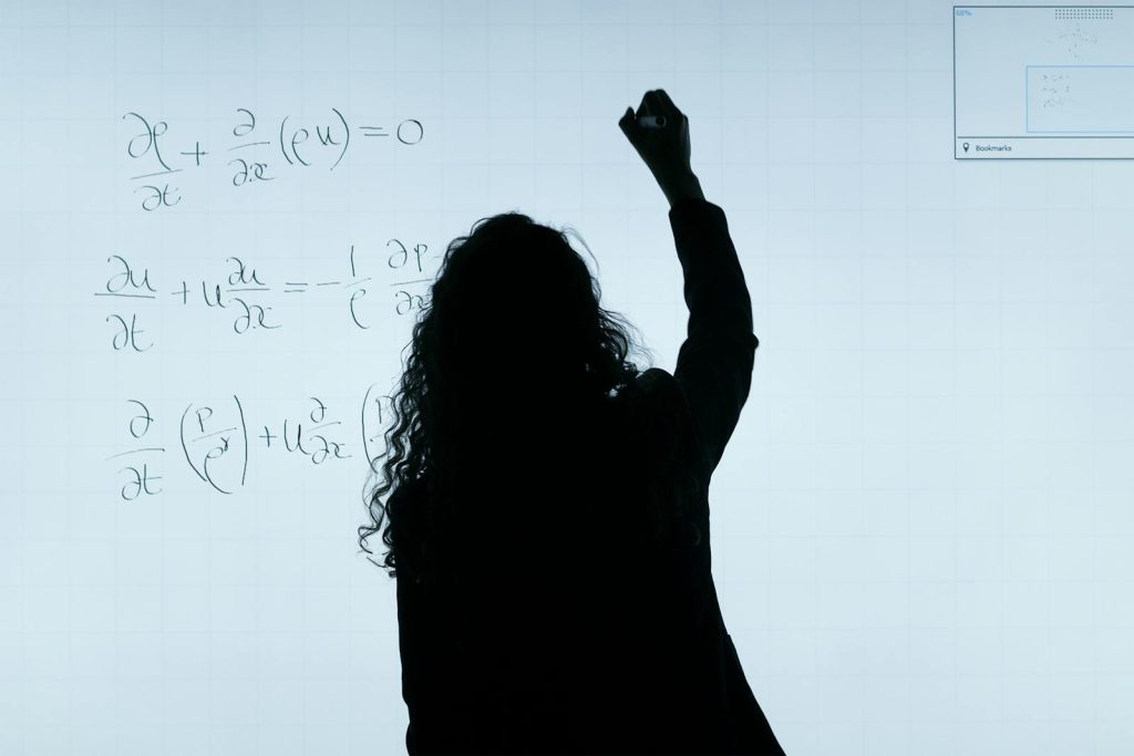 This Female Teacher Rides Small Motorboat Daily to Go to School | Big Thumbs Up for Dedication, Sacrifices 5 A silhouette of a woman writing mathematical equations on a large whiteboard, representing education and analysis.