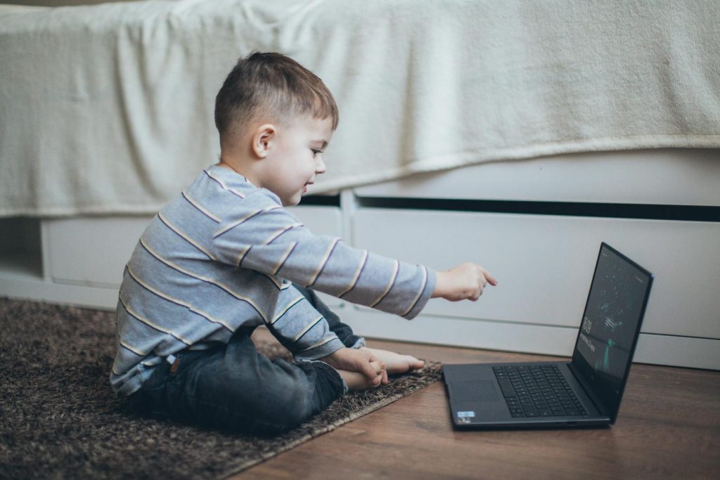 Updated Measures: How DepEd Ensures Learning Continues During Calamities? - Minimize Disruptions 5 Young boy engaging with laptop, enjoying learning in a cozy home setting.